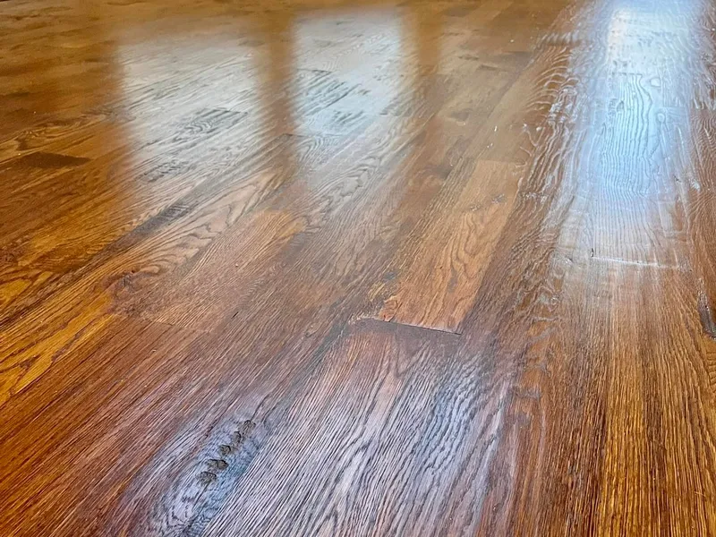 Close view of medium-brown hardwood flooring in a room with a bay window.