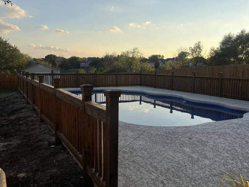 Wood fence at dusk with a pool in the foreground.