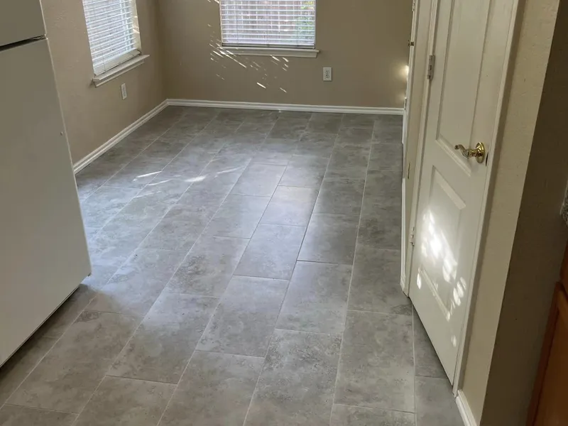 Kitchen breakfast area with large gray floor tile, beige walls, and white trim.