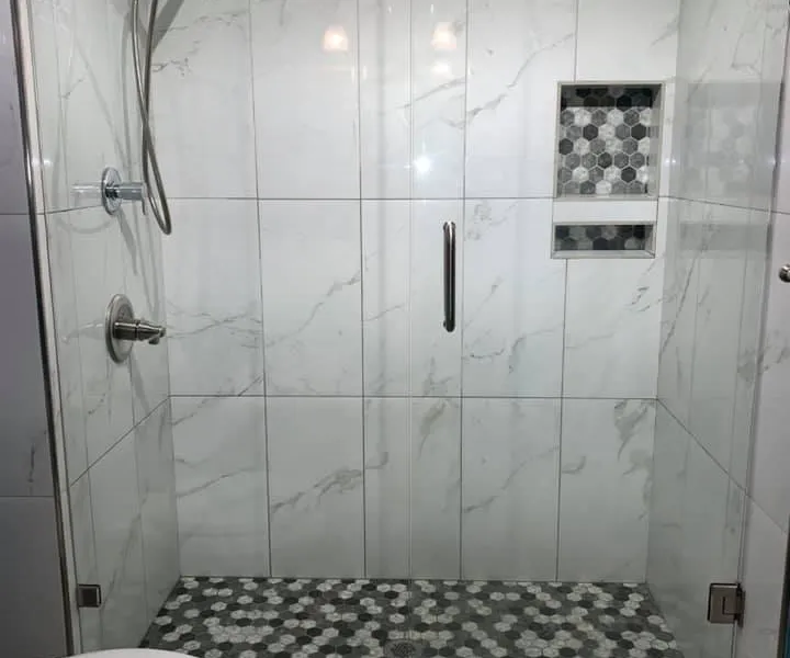 Toilet and walk-in shower with marble-look tile and chrome fixtures